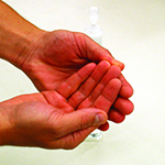 Photo of person applying hand sanitizer over and under finger nails