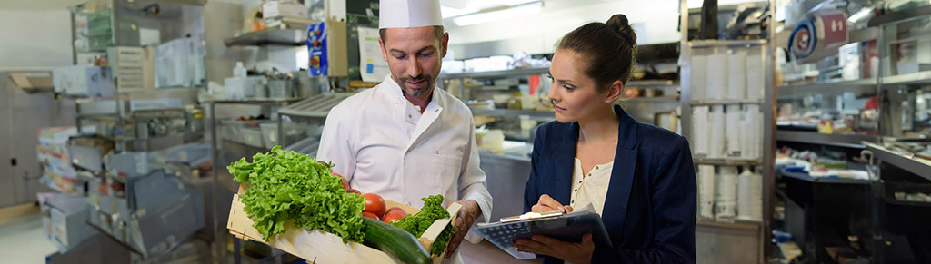 Photo of Health inspector and cook reviewing a checklist