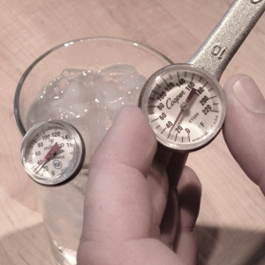 Hands adjusting a thermometer in ice slush with a wrench