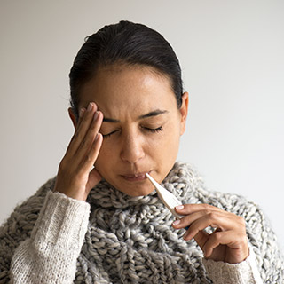 Photo of woman taking temperature with a thermometer