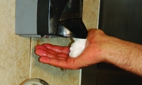 A person getting soap from a soap dispenser.
