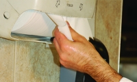 A person grabbing paper towel sheets from a paper towel dispenser. 
