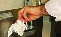 A person using a paper towel to turn off the tap water.