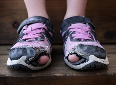 Photo of a child's shoes with holes in the toes