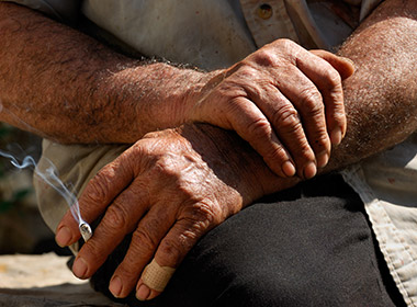 Photo of weathered working hands holding a cigarette