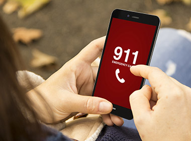 Photo of a woman dialing 911 on her smartphone