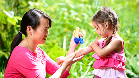 Photo of a woman applying sunscreen to a child