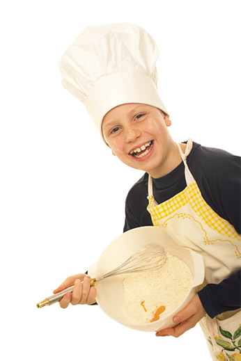 Photo of a boy in a chef hat stirring a bowl of ingredients