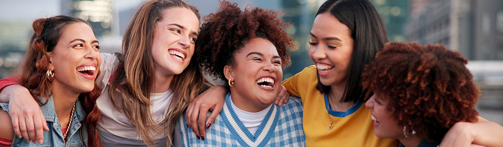 Group of young women with arms around one another, smiling