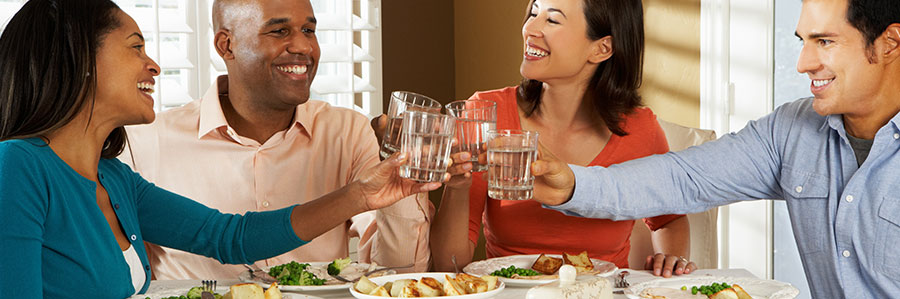 four adults holding a cup of water toasting 