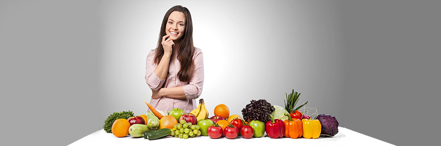 woman standing behind a table of fruit and vegetables 