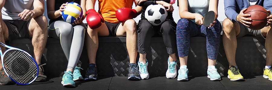 people sitting on bench holding several sport equipment
