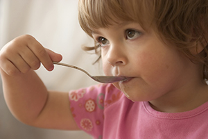Toddler eating with a spoon.